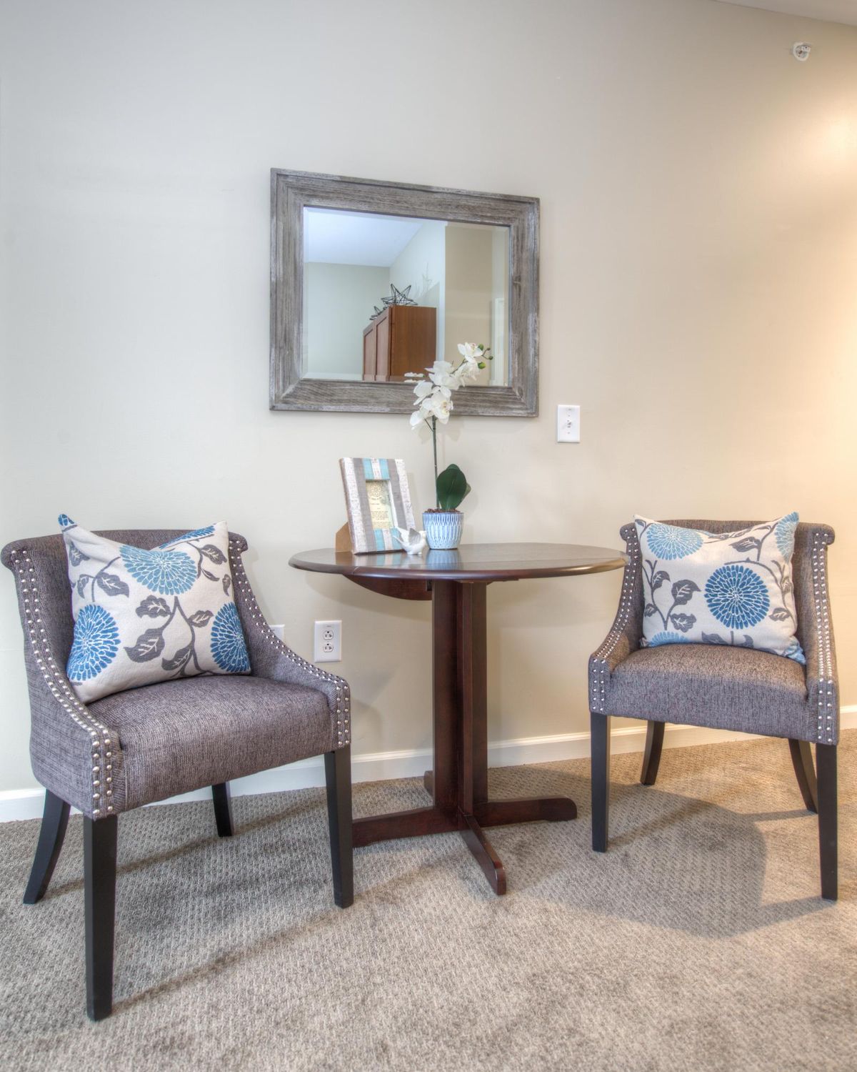 A cozy corner with two upholstered chairs, a small round table, and a decorative mirror.