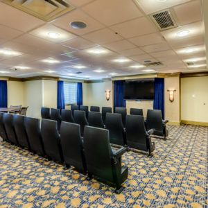 An empty conference room featuring theater-style seating and a projector screen.