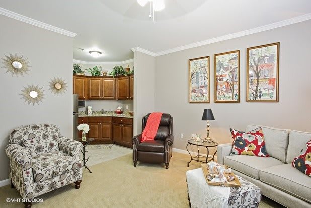 A cozy living room with a blend of comfortable seating and decorative elements, featuring a small kitchenette in the corner.
