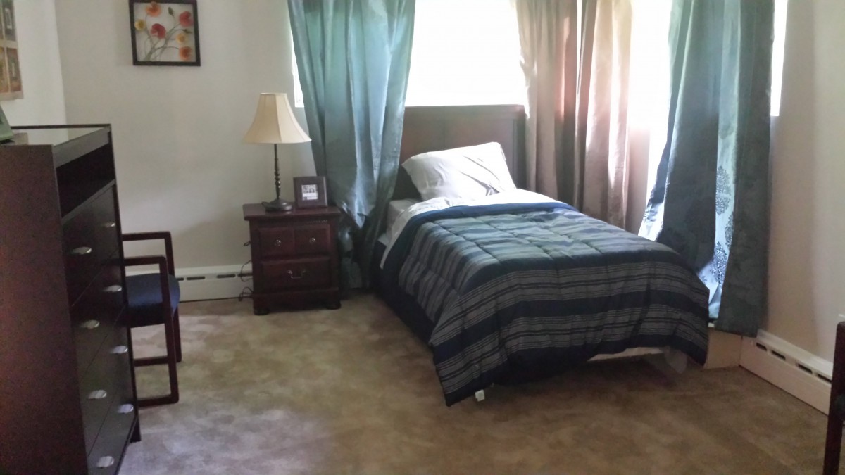 A cozy bedroom with a single bed and natural light streaming in through the curtains.
