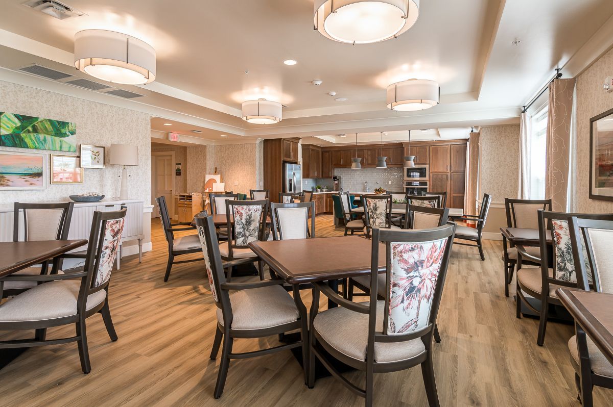 A modern dining area with multiple tables and chairs, featuring stylish lighting and an open kitchen space.