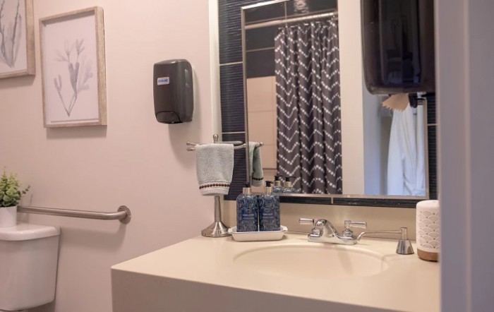 A clean and modern bathroom with a sink, mirror, and shower curtain.