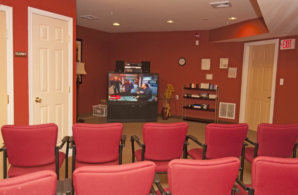A cozy home theater setup with red chairs facing a large television.