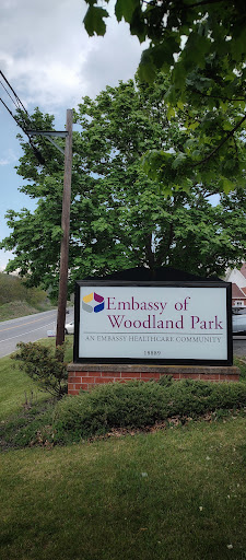 Signage for the Embassy of Woodland Park, surrounded by greenery.