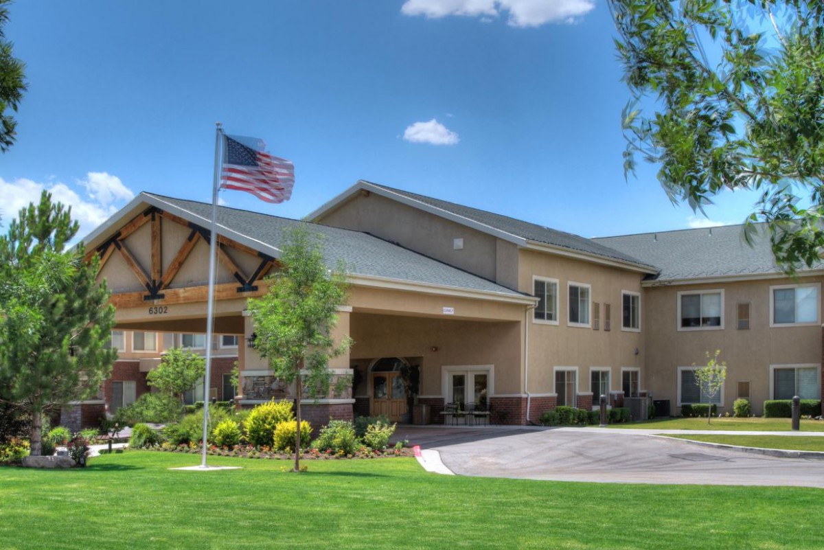 A well-maintained building with an American flag and a green lawn under a blue sky with clouds.