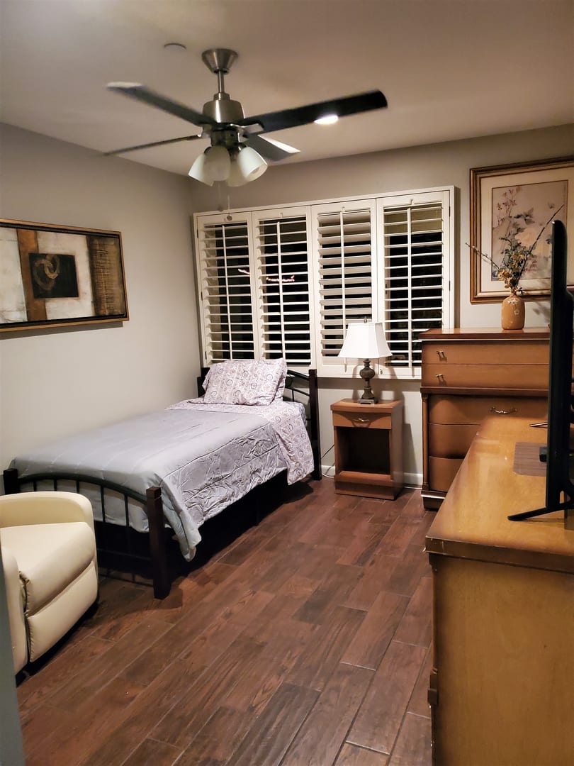 A cozy bedroom with a single bed, nightstand, and wooden furniture.