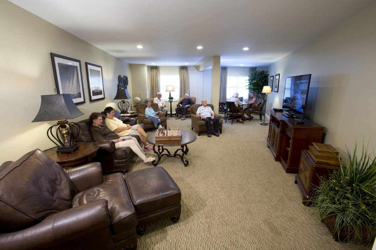 A cozy living room with several people relaxing and watching television.