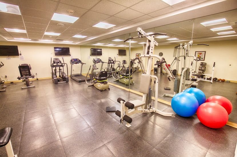 A well-equipped gym featuring various exercise machines, treadmills, and workout accessories in a spacious indoor setting.