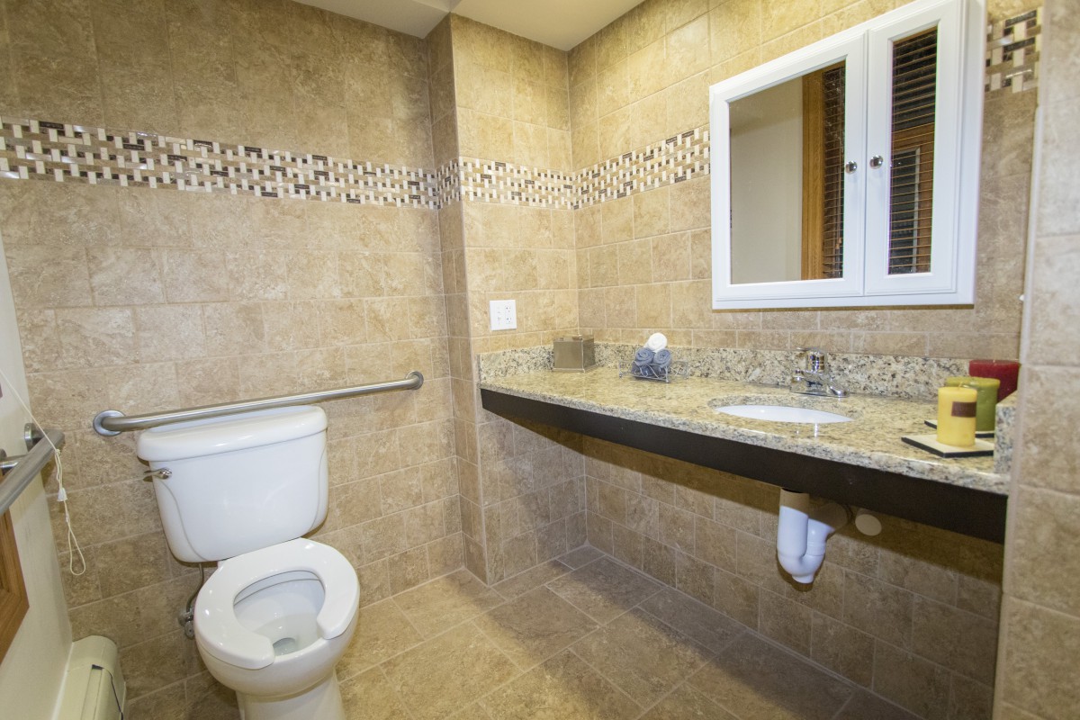 A modern bathroom with tile walls, a toilet, a sink, and a mirror.