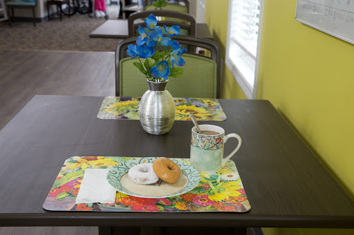 A cozy dining setup with a floral centerpiece, a cup of coffee, and a donut on vibrant placemats.