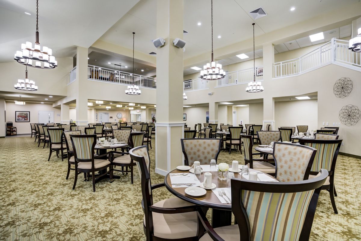 An elegant and spacious dining hall with neatly arranged tables and chairs under stylish chandeliers.