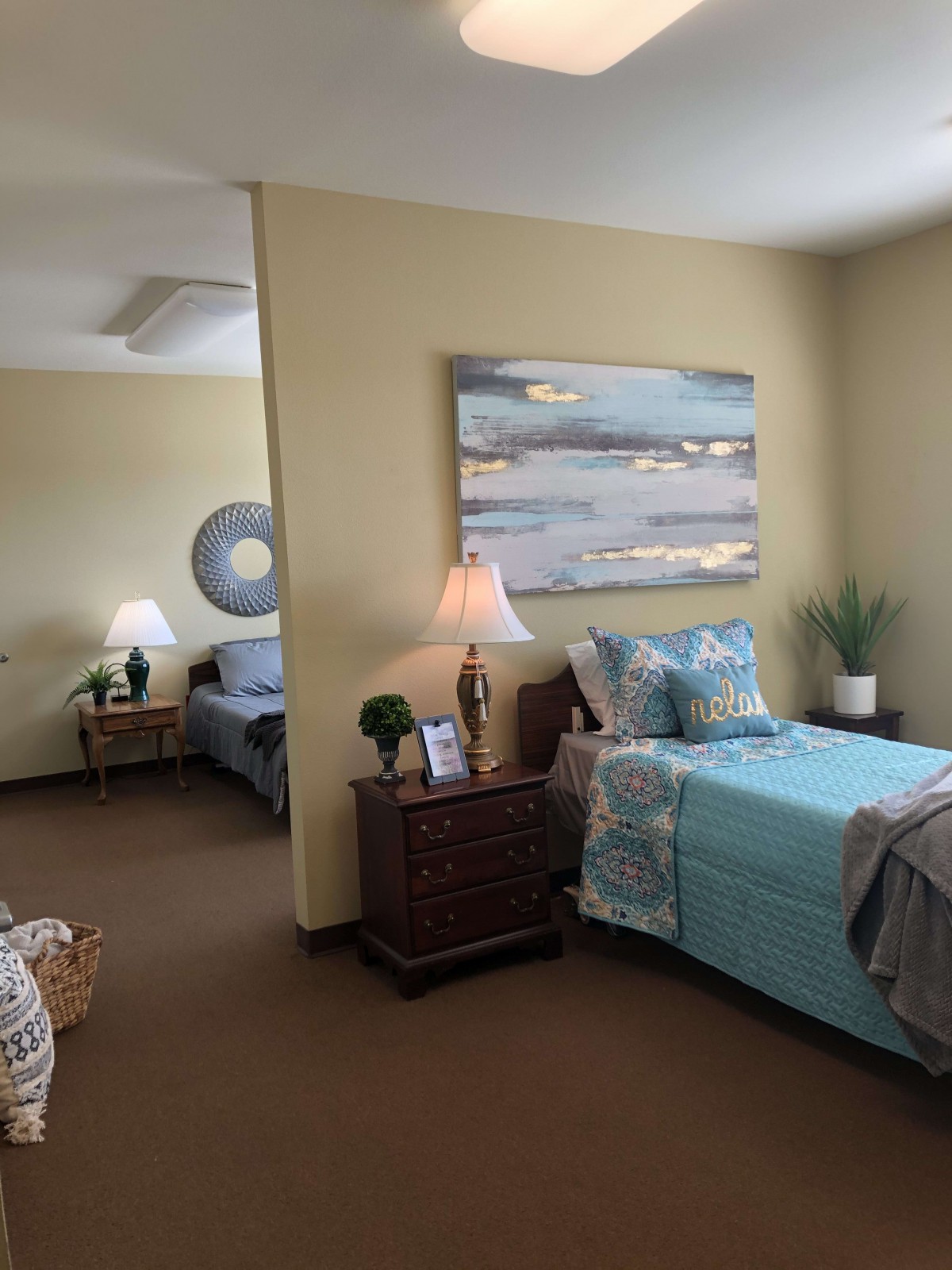 A cozy bedroom with twin beds, decorated with a large painting and soft lighting.