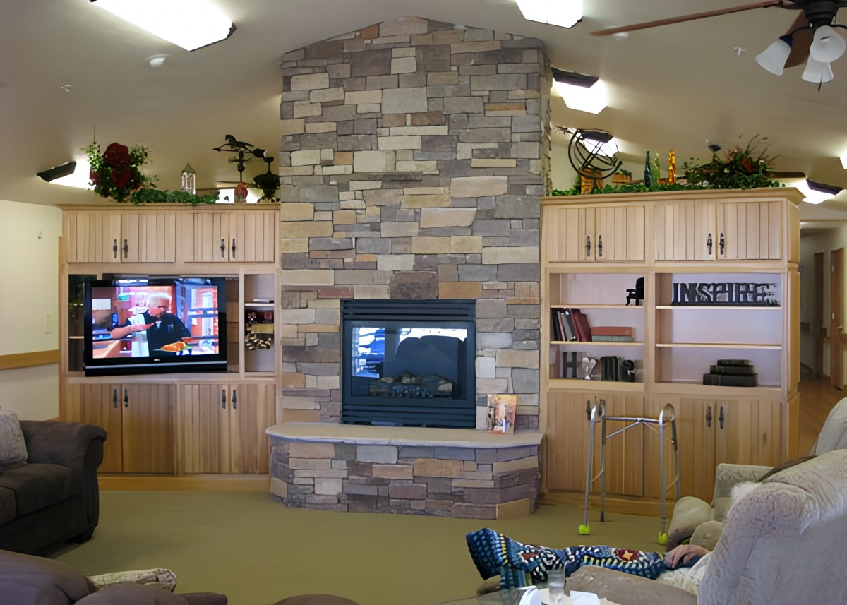 A cozy living room with a stone fireplace and built-in shelves surrounding a television.