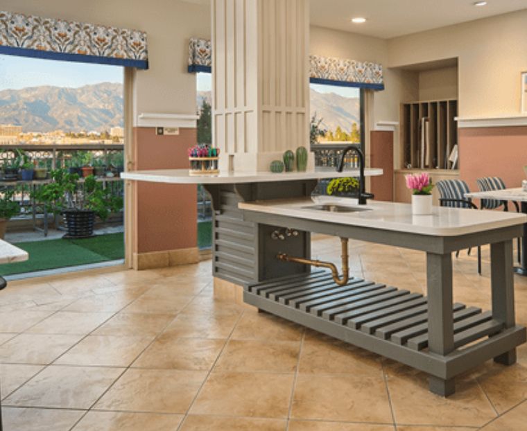 A modern kitchen interior featuring an island counter and ample natural light from large windows.