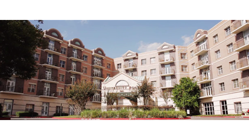 A view of modern apartment buildings with lush landscaping and a clear blue sky.