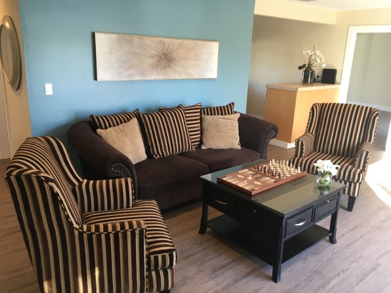 A cozy living room featuring a sofa and armchairs with striped upholstery, accented by a coffee table and modern decor.