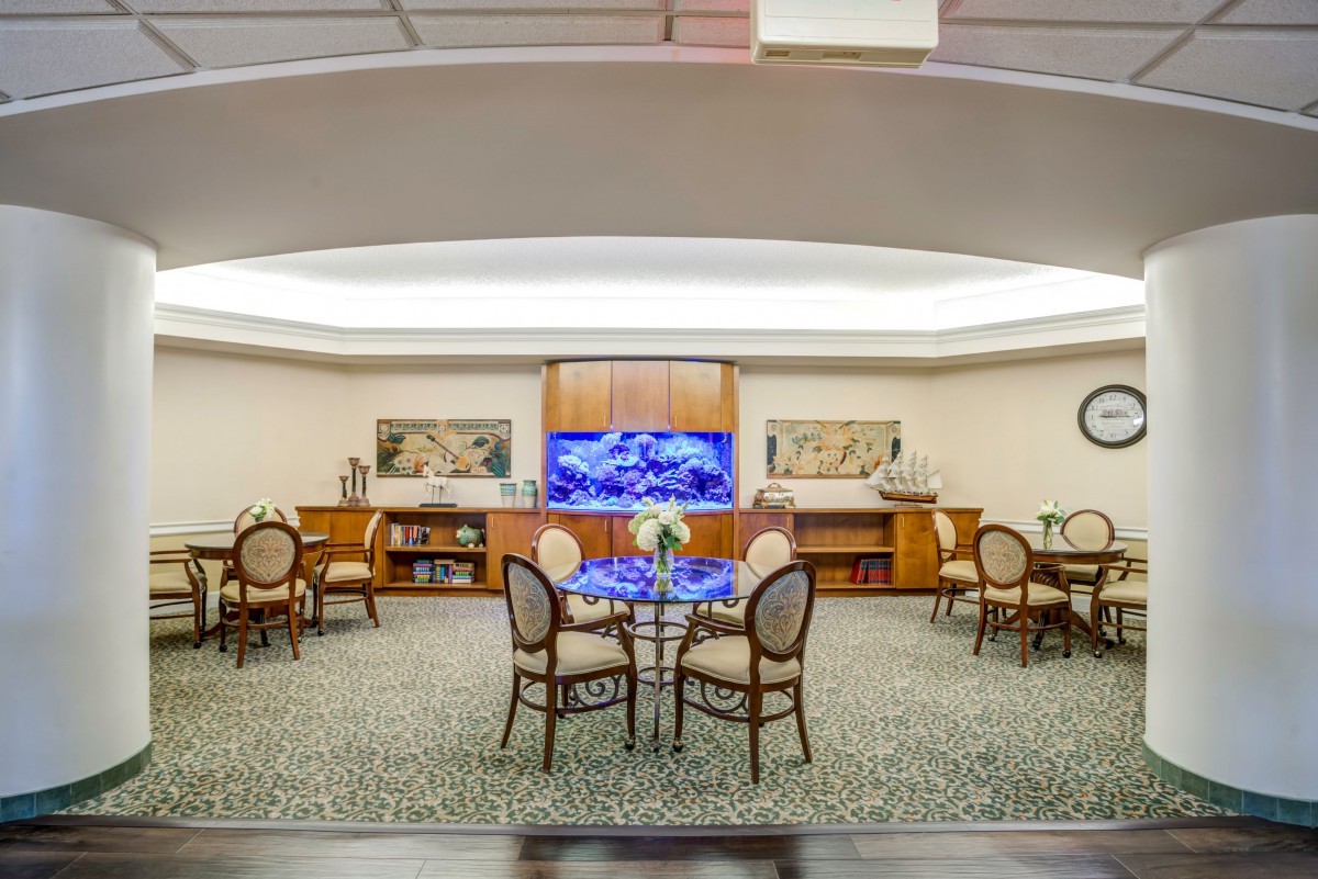 A spacious lobby area with elegant chairs and tables, featuring decorative elements and a large display screen.