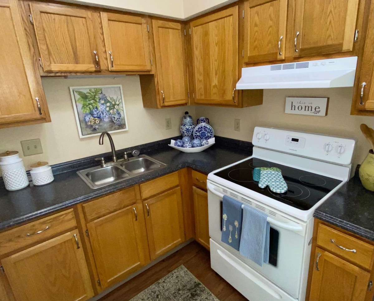 A cozy kitchen with wooden cabinets, a stove, and a double sink.