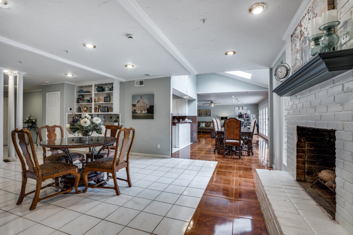 A modern dining room with elegant furniture and a blend of tiled and wood flooring.