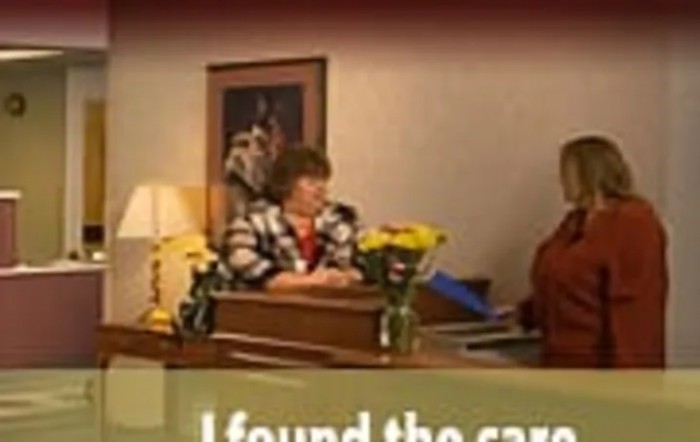 Office scene with people at a desk and flowers on the table.