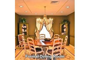 A formal dining room with a wooden dining table, chairs, and a chandelier.