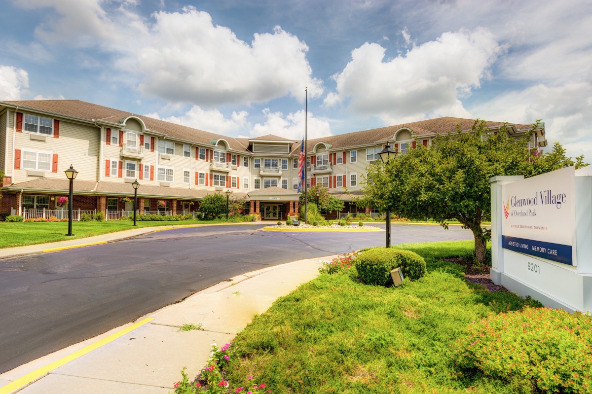 A residential building with a landscaped exterior and a circular driveway under a cloudy sky.