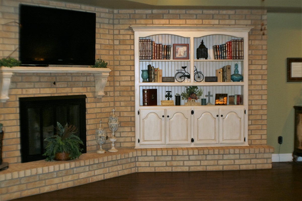 A cozy living room corner with a brick fireplace and built-in bookshelf.