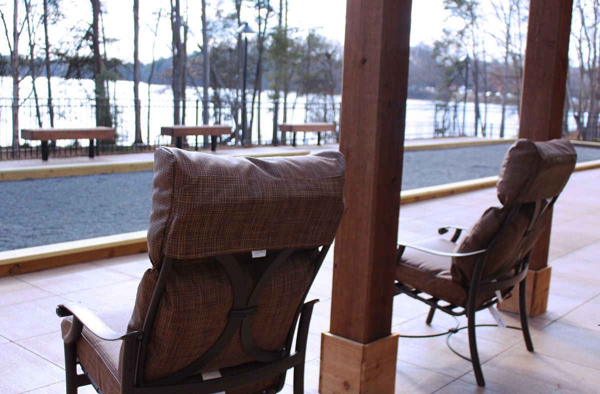 A serene patio with comfortable seating overlooking a lake and trees.