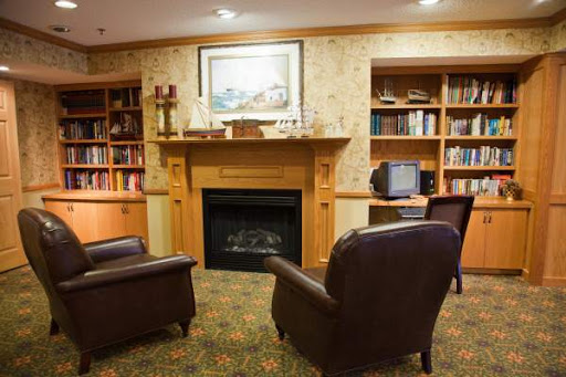 A cozy living room featuring a fireplace and comfortable seating surrounded by bookshelves.