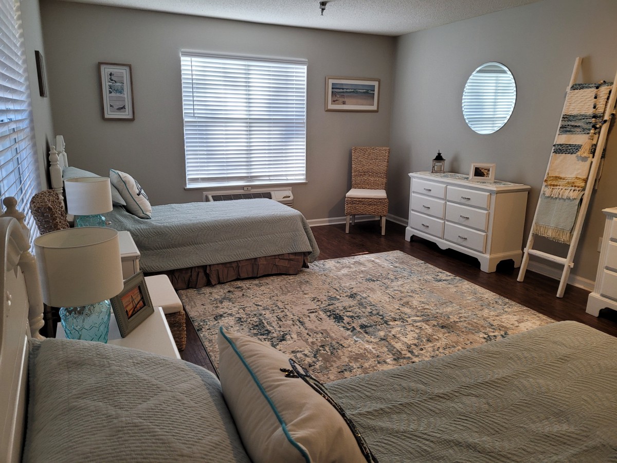 A cozy bedroom with two twin beds, a rug, and elegant furniture.