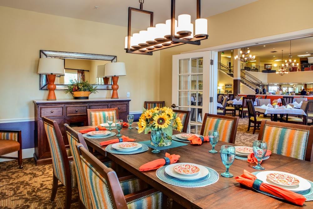 A warmly decorated dining room with a wooden table, striped chairs, and sunflowers as a centerpiece.