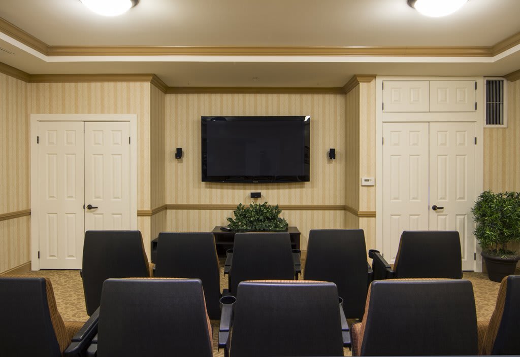 A small conference room with rows of chairs facing a wall-mounted television.