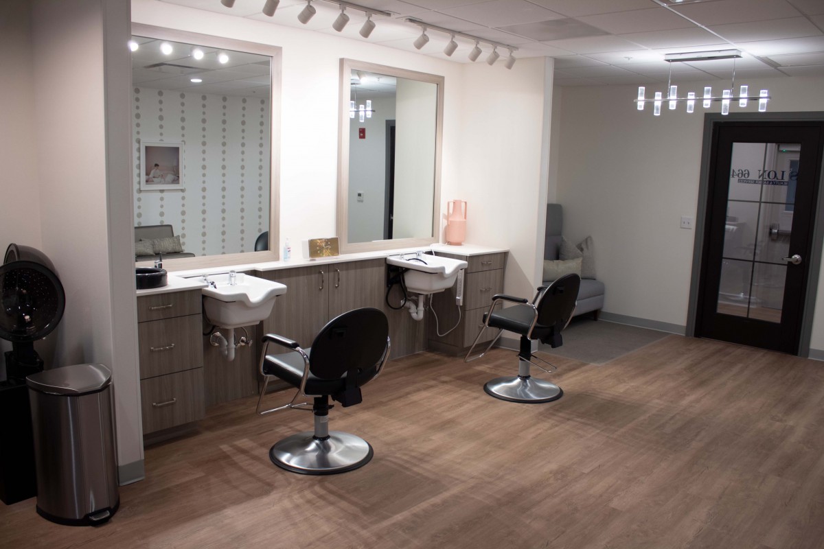 A modern hair salon interior featuring styling chairs, mirrors, and sinks with bright lighting.
