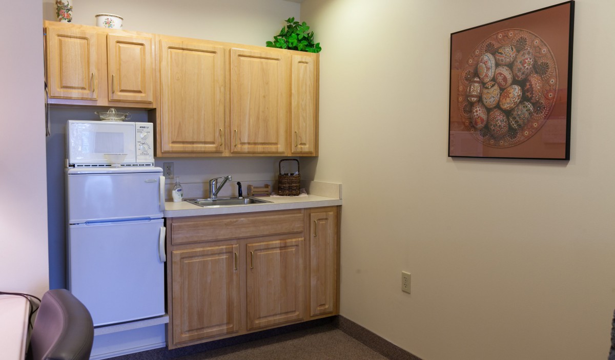 A small kitchen area with wooden cabinets, a sink, and a refrigerator.