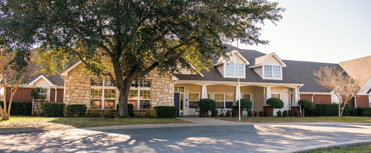 A picturesque suburban house with a large tree in the front yard.