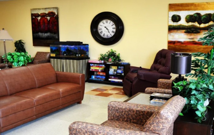 A cozy waiting room with comfortable seating, a large wall clock, and a fish tank.