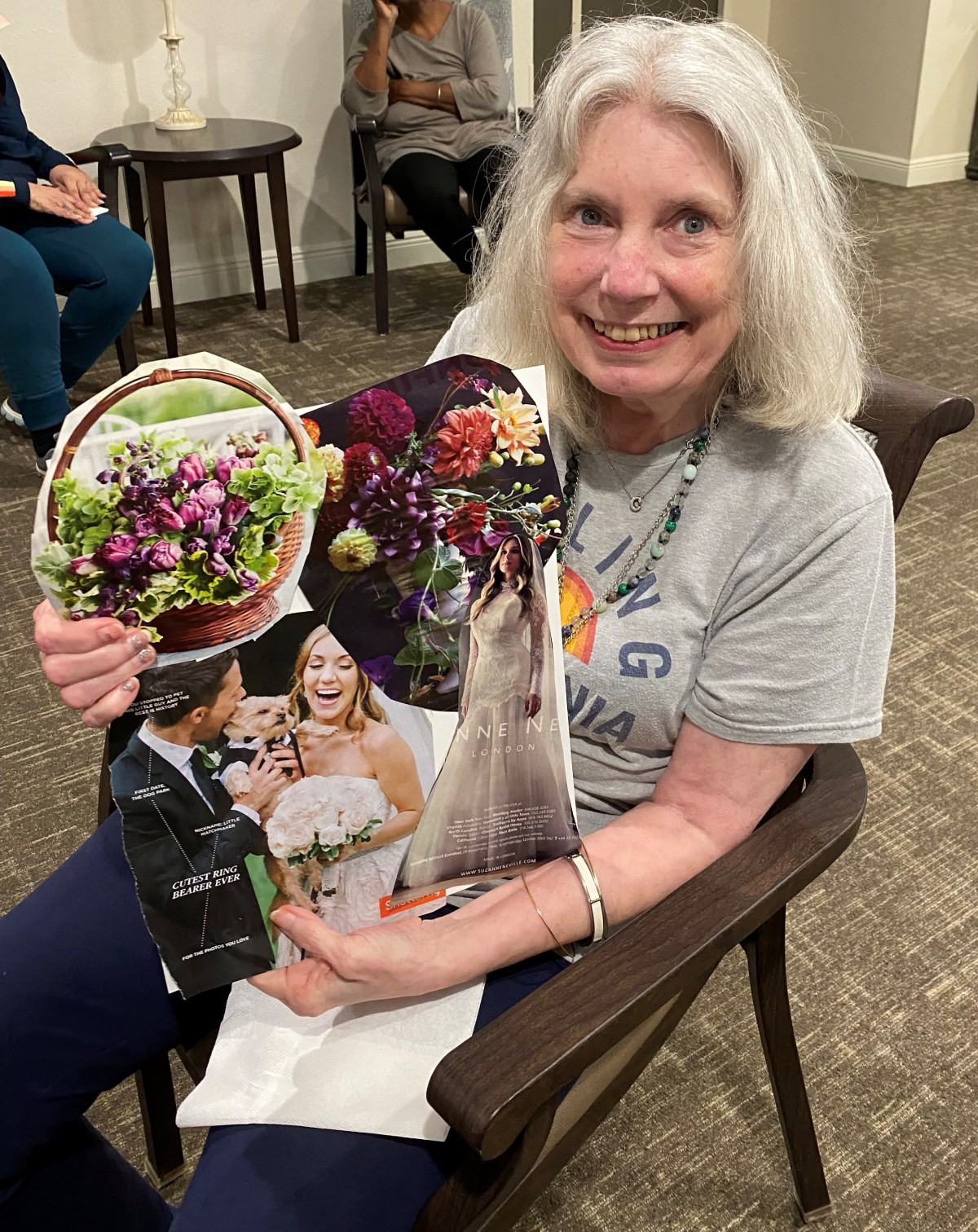 A woman holding a colorful collage featuring flowers and people, smiling brightly.