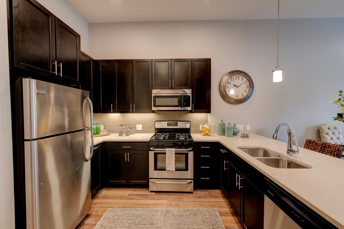 A modern kitchen with dark cabinets and stainless steel appliances.
