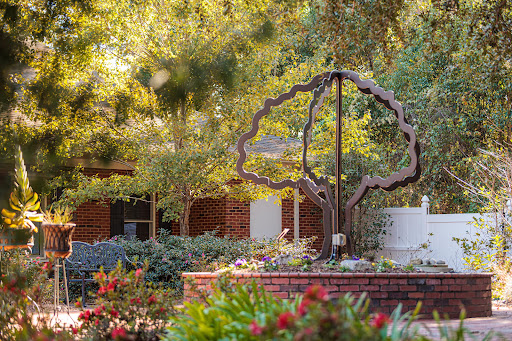 A beautifully landscaped garden featuring a tree sculpture surrounded by vibrant flowers.