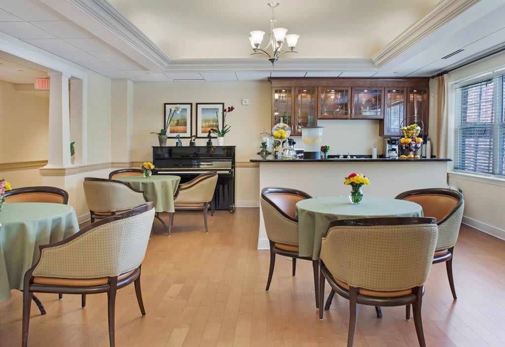 A cozy dining area with a piano and kitchen, featuring elegant seating and vibrant decor.