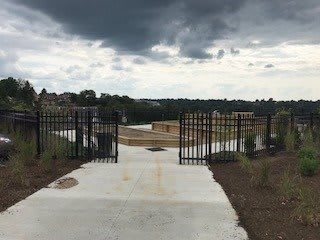 A gated entrance leads to a pathway under a cloudy sky.