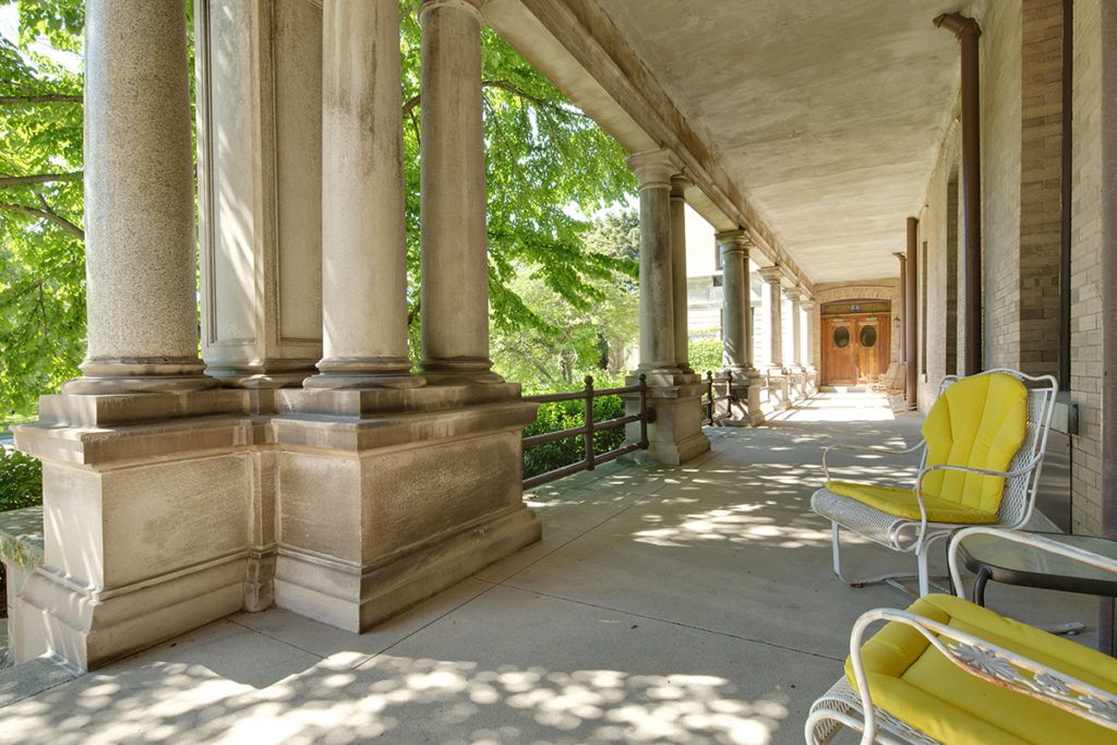 A sunlit outdoor corridor with columns and seating.