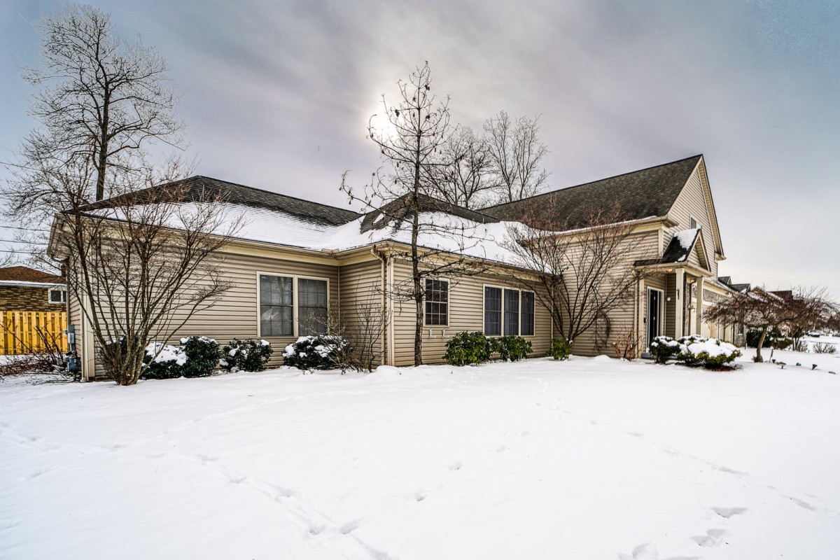 A residential house surrounded by a snowy landscape under an overcast sky.
