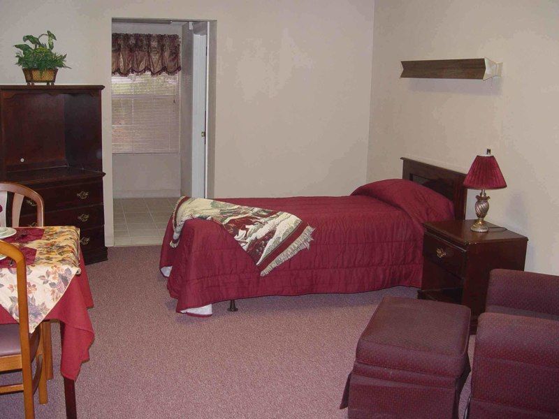 A cozy bedroom with a single bed and red bedding, featuring traditional furniture and decor.