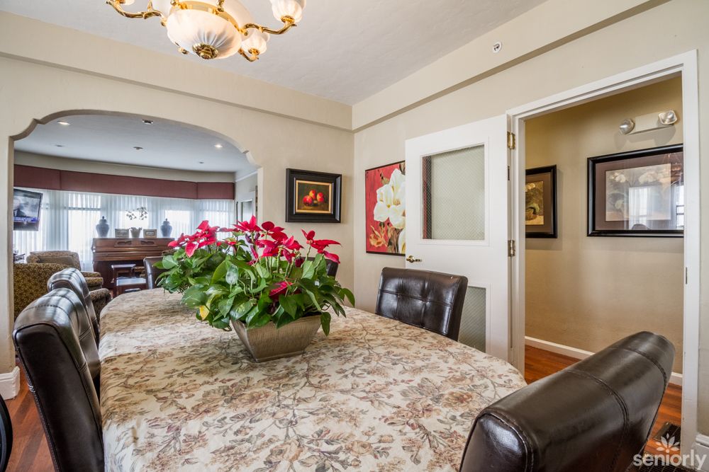 A beautifully decorated dining room featuring a floral centerpiece, elegant chandelier, and tasteful artwork.