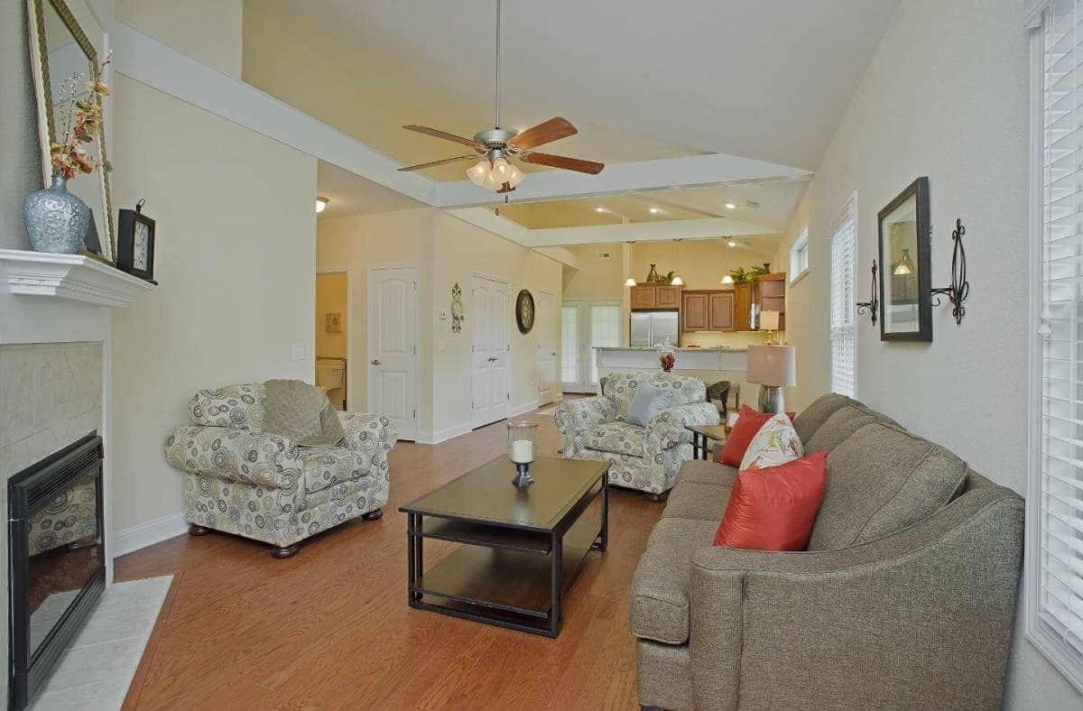 A spacious living room with an open floor plan, featuring comfortable furniture and a view into the kitchen.