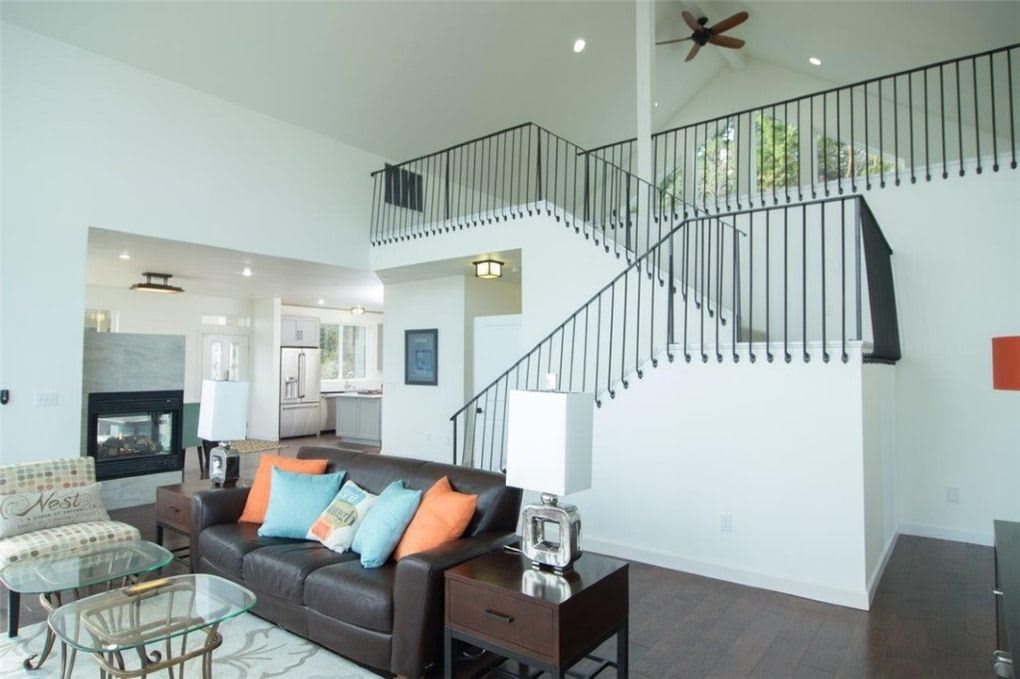 A modern living room with an open concept design, featuring a staircase and stylish decor.