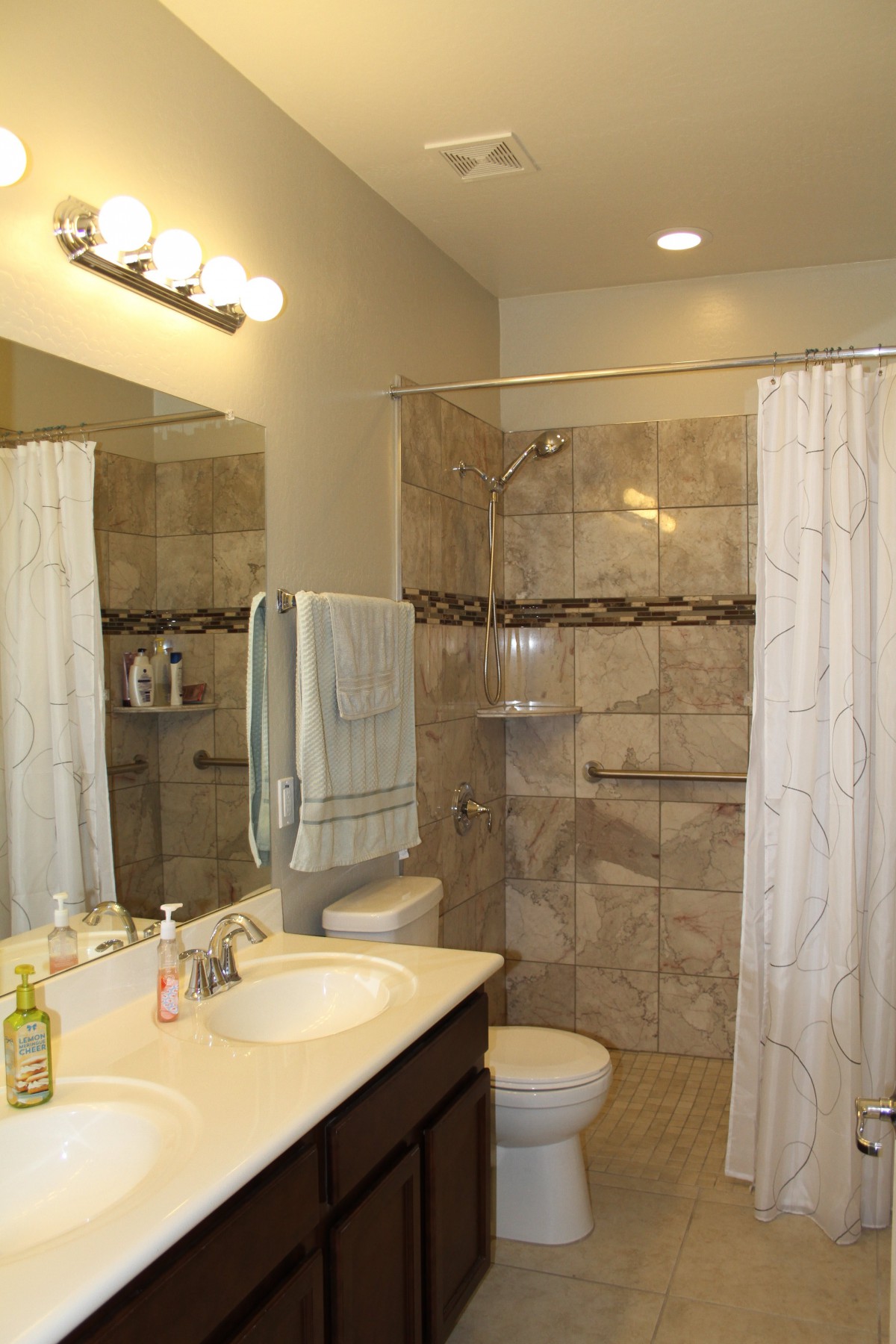 A modern bathroom with a shower, sink, and mirror.
