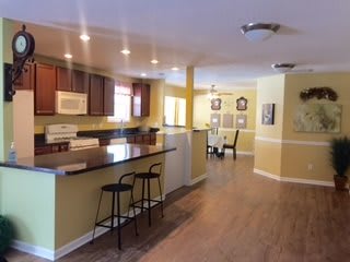 An open-concept kitchen and dining area featuring modern wood flooring, recessed lighting, and bar seating.