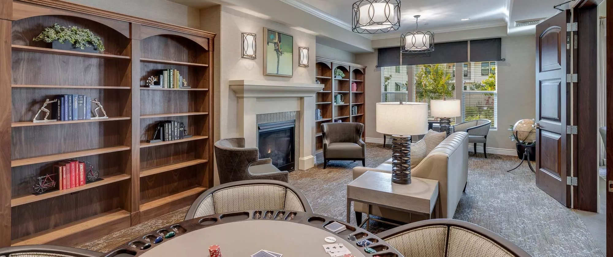 A cozy living room features elegant furniture, bookshelves, and a warm fireplace.